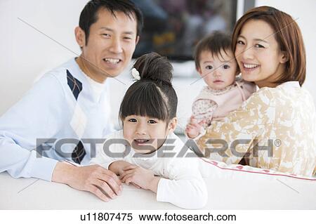 Stock Photography - Portrait of family sitting on sofa. Fotosearch