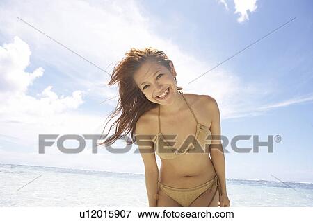 Stock Photo - Portrait of young woman standing in water, Guam, USA. Fotosearch