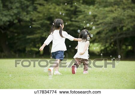 Picture - Sisters chasing bubbles. Fotosearch