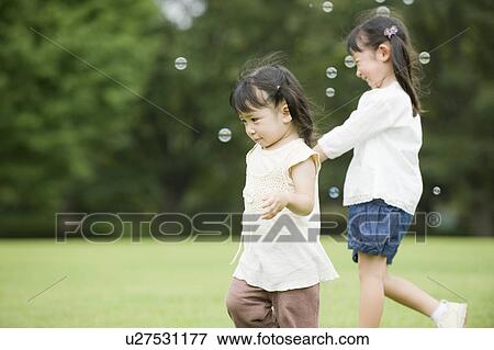 Stock Photo - Sisters chasing bubbles. Fotosearch