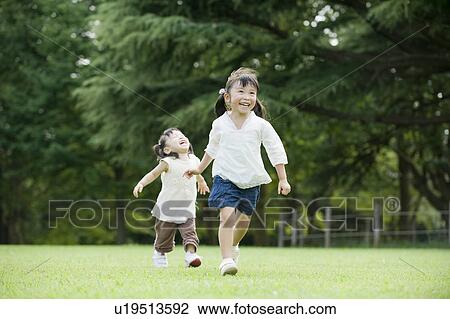 Stock Image - Sisters playing in the Park. Fotosearch