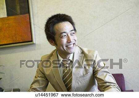 Stock Photo - Smiling businessman waiting at reception area. Fotosearch