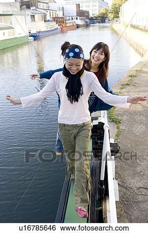 Stock Photograph - Two Young Women Balancing by Edge of River. Fotosearch