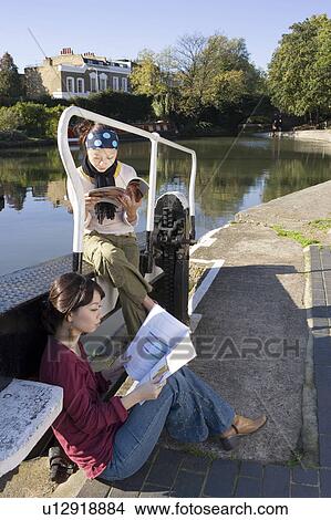 Picture - Two Young Women Studying by River. Fotosearch