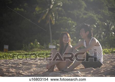 Picture - Young couple talking on beach, Guam, USA. Fotosearch
