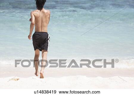 Young man running on beach, Guam USA View Large Photo Image Stock Photo - Young man running on beach, Guam USA. Fotosearch