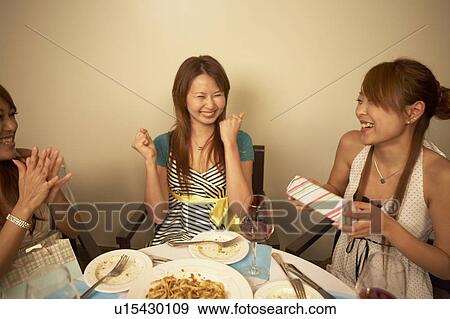 Stock Photo - Young woman getting a gift from a friends. Fotosearch