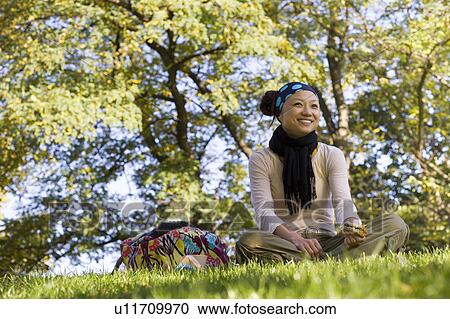 Stock Image - Young Woman Having Lunch in Park. Fotosearch
