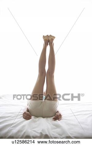 Picture - Young woman laying down and stretching. Fotosearch