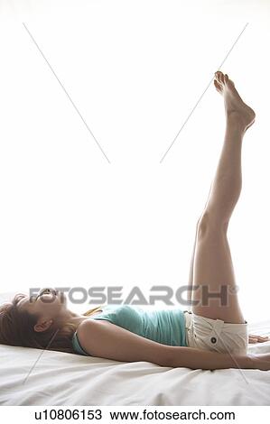 Stock Image - Young woman laying down and stretching. Fotosearch
