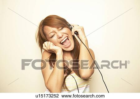 Stock Image - Young woman listening to music. Fotosearch
