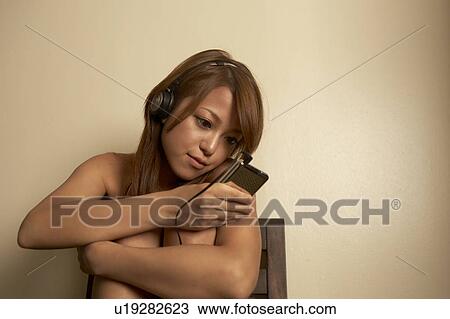 Stock Image - Young woman listening to music. Fotosearch