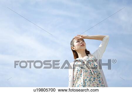 Stock Image - Young woman looking at sun. Fotosearch