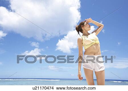 Picture - Young woman looking at the sun, Guam, USA. Fotosearch