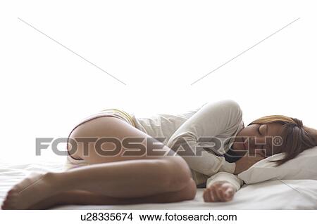 Young woman lying down on bed sleeping View Large Photo Image Picture - Young woman lying down on bed sleeping. Fotosearch