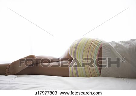 Young woman lying down on bed sleeping View Large Photo Image Stock Image - Young woman lying down on bed sleeping. Fotosearch