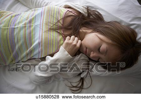 Young woman lying down on bed sleeping View Large Photo Image Stock Photo - Young woman lying down on bed sleeping. Fotosearch