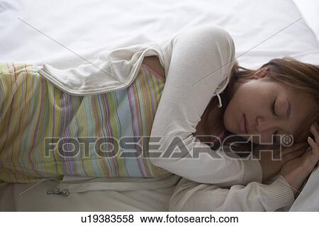 Young woman lying down on bed sleeping View Large Photo Image Stock Photo - Young woman lying down on bed sleeping. Fotosearch