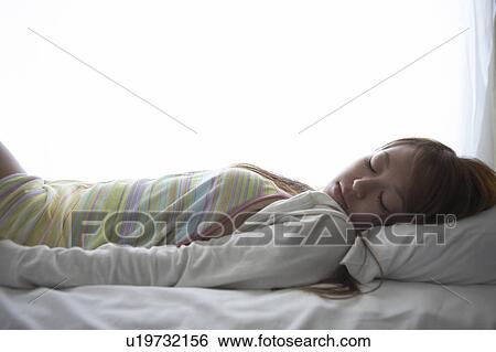 Young woman lying down on bed sleeping View Large Photo Image Stock Photograph - Young woman lying down on bed sleeping. Fotosearch