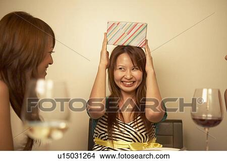 Young woman placing gift on top of her head View Large Photo Image Picture - Young woman placing gift on top of her head. Fotosearch