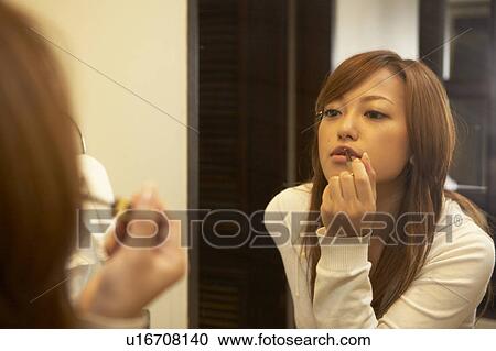 Stock Image - Young woman putting lip gloss on. Fotosearch