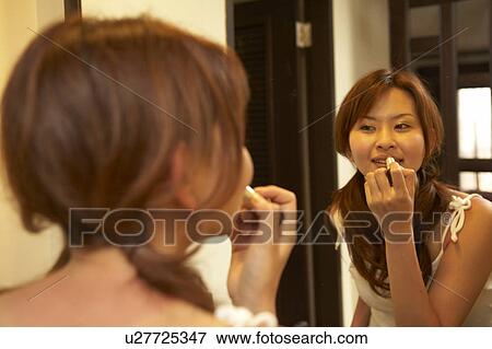 Stock Photo - Young woman putting lipstick on. Fotosearch