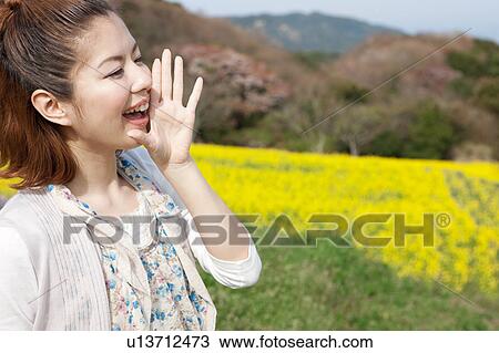 Stock Image - Young woman shouting in oilseed rape field. Fotosearch
