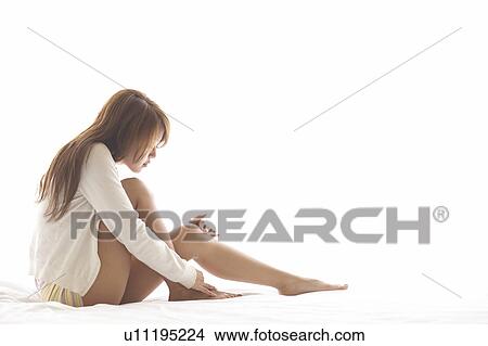 Young woman sitting on bed View Large Photo Image Picture - Young woman sitting on bed. Fotosearch