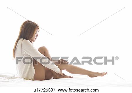 Young woman sitting on bed View Large Photo Image Stock Photo - Young woman sitting on bed. Fotosearch