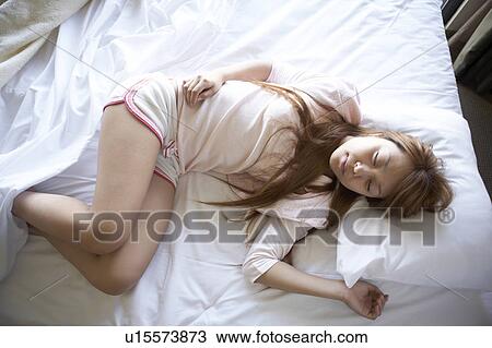 Stock Image - Young woman sleeping in bed. Fotosearch