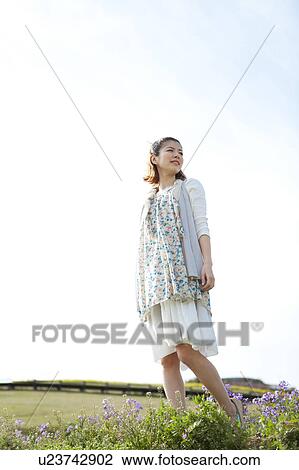 Young woman standing and looking away View Large Photo Image Stock Image - Young woman standing and looking away. Fotosearch
