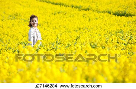 Picture - Young woman standing in oilseed rape field . Fotosearch
