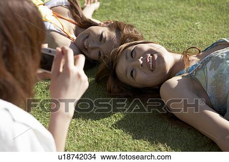 Picture - Young woman taking picture of friends, Guam, USA. Fotosearch