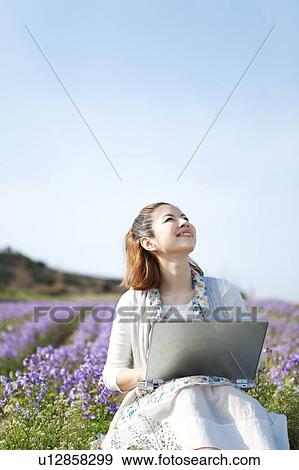 Young woman using laptop in front of flowers View Large Photo Image Stock Photo - Young woman using laptop in front of flowers. Fotosearch