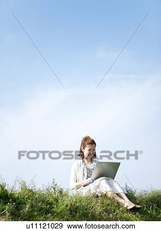Stock Photo - Young woman using laptop outdoors. Fotosearch