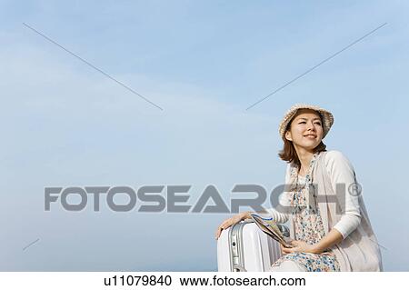 Stock Image - Young woman with map and suitcase. Fotosearch
