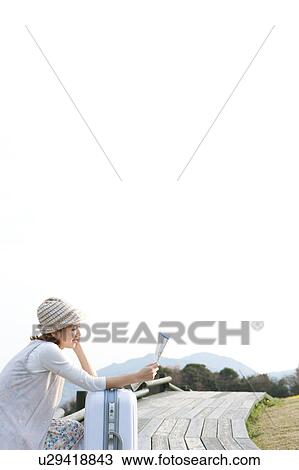 Stock Image - Young woman with map and suitcase. Fotosearch