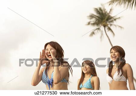 Stock Image - Young women shouting and laughing in bikini, Guam, USA. Fotosearch