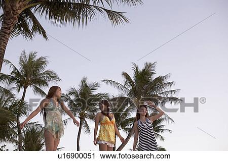 Stock Image - Young women standing on beach, Guam, USA. Fotosearch