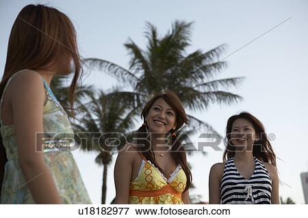 Stock Photo - Young women standing on beach, Guam, USA. Fotosearch