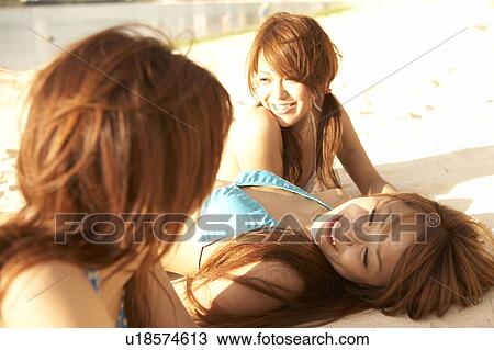 Stock Image - Young women sunbathing on beach, Guam, USA. Fotosearch