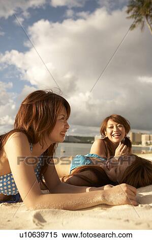 Stock Photography - Young women sunbathing on beach, Guam, USA. Fotosearch