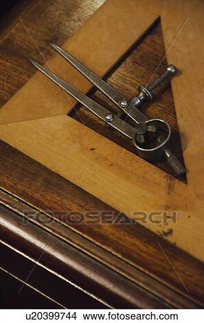 Picture - Antique set square and pair of compasses on wooden table. Fotosearch