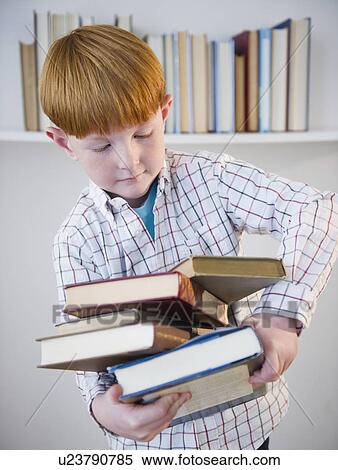 Stock Photography - Boy (8-9) carrying stacked books. Fotosearch