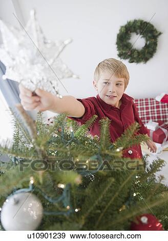 Boy (8-9) decorating Christmas tree View Large Photo Image Stock Photo - Boy (8-9) decorating Christmas tree. Fotosearch
