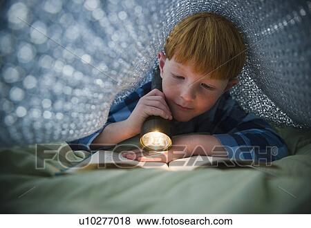 Boy (8-9) reading book under bed covers View Large Photo Image Stock Photo - Boy (8-9) reading book under bed covers. Fotosearch
