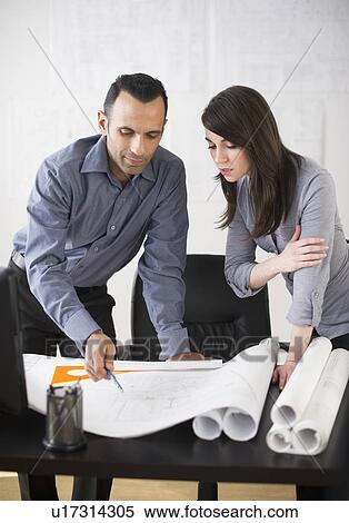 Stock Photography - Business man and woman studying blueprints. Fotosearch