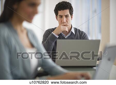 Business man and woman using laptops in office View Large Photo Image Stock Image - Business man and woman using laptops in office. Fotosearch