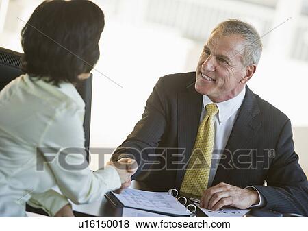 Stock Photo - Businesswoman and businessman shaking hands. Fotosearch