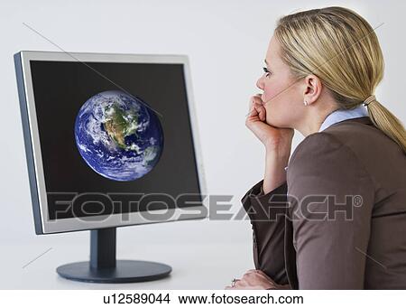 Businesswoman looking at monitor with globe View Large Photo Image Picture - Businesswoman looking at monitor with globe. Fotosearch
